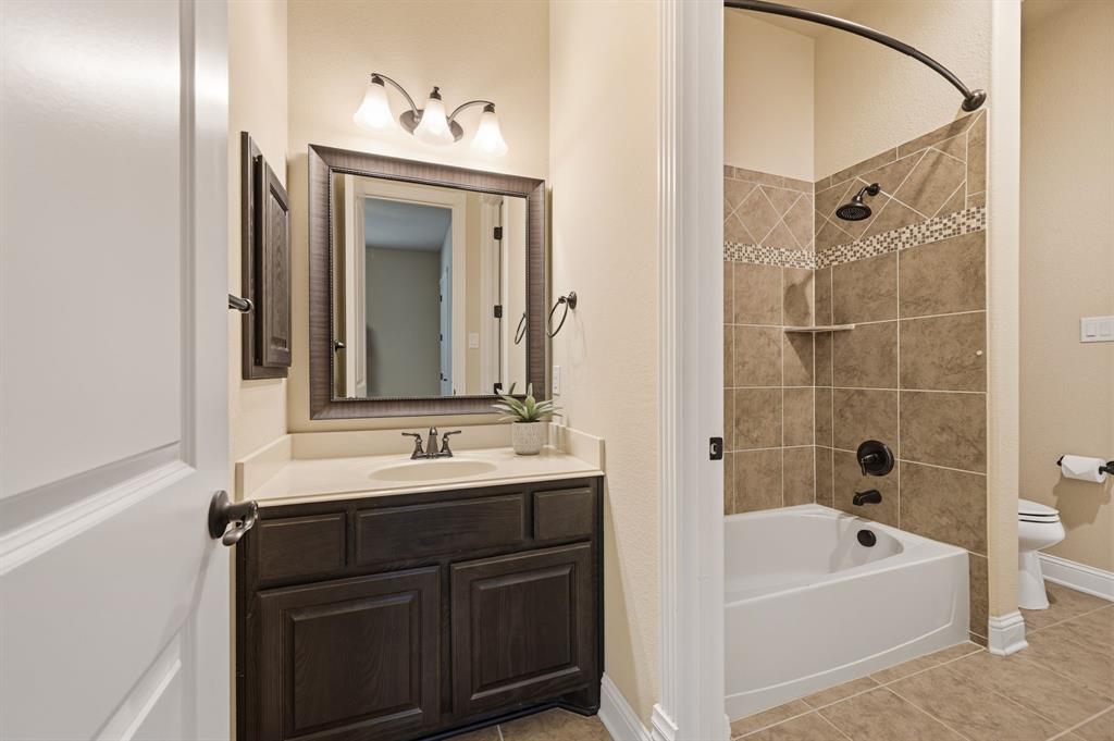 7013 Handel Colleyville, TX 76034 - Photo 27 of 37 Bathroom featuring a dark wood vanity with a white countertop, framed mirror, and three-light vanity fixture