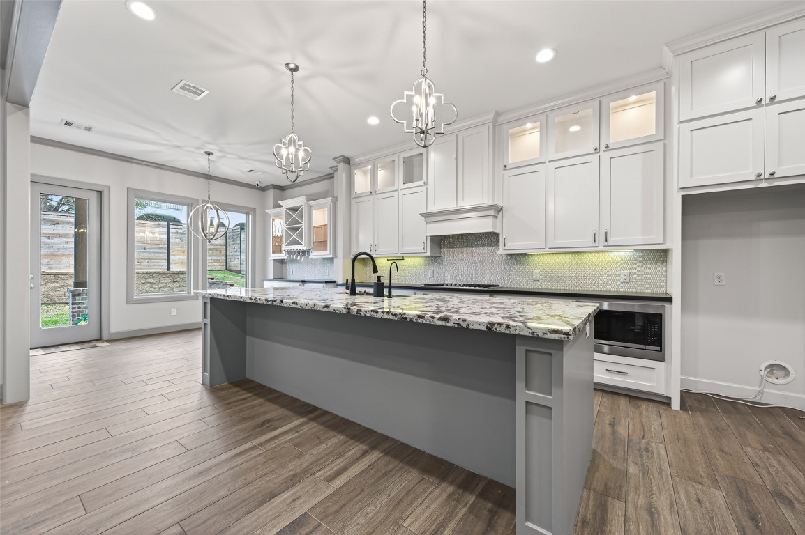 12379 Pebble View Drive Conroe, TX 77304 - Photo 8 of 49 a large kitchen with granite countertop a stove top oven a sink a dining table and chairs with wooden floor