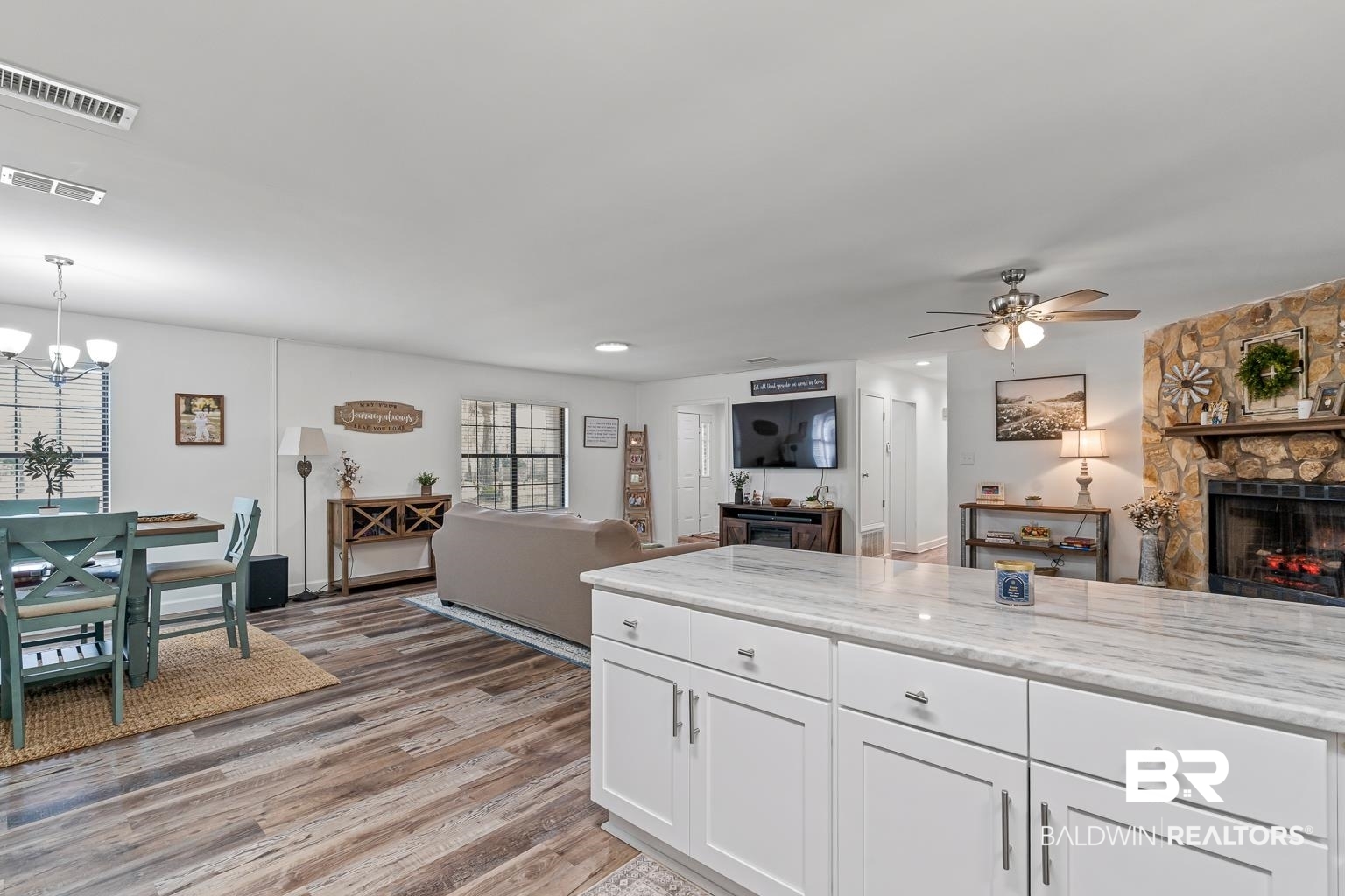 6801 Piney Woods Road Foley, AL 36535 - Photo 74 of 74 Kitchen with open floor plan, white cabinets, a fireplace, light stone counters, and light wood-style floors