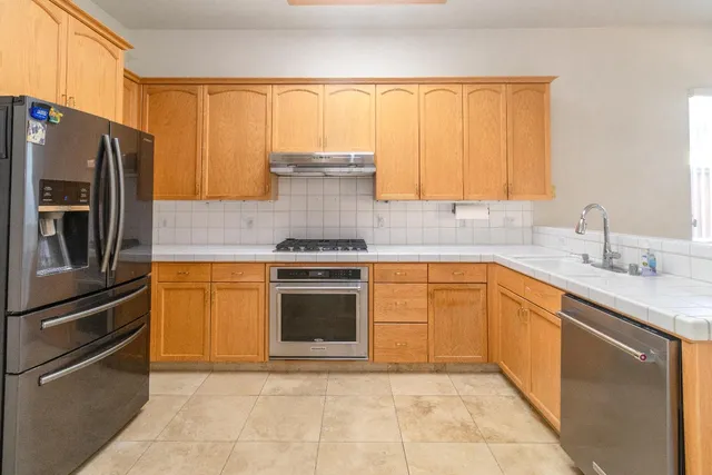 a kitchen with stainless steel appliances granite countertop a stove a sink and a refrigerator