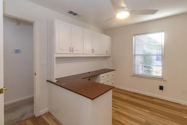 an empty room with wooden floor and cabinets