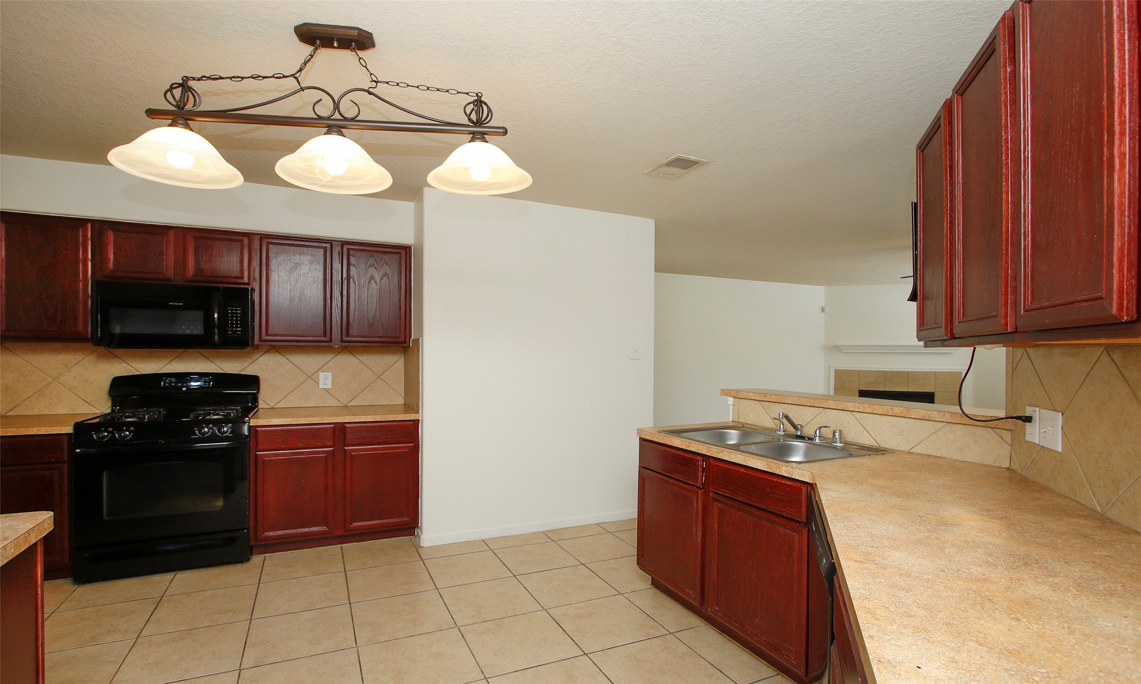 9812 Expedition Trail Conroe, TX 77385 - Photo 15 of 37 a kitchen with a stove a microwave and wooden cabinets
