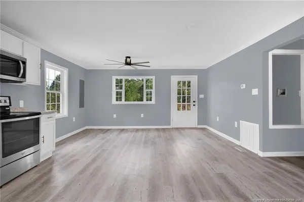 a view of an empty room with a window and wooden floor