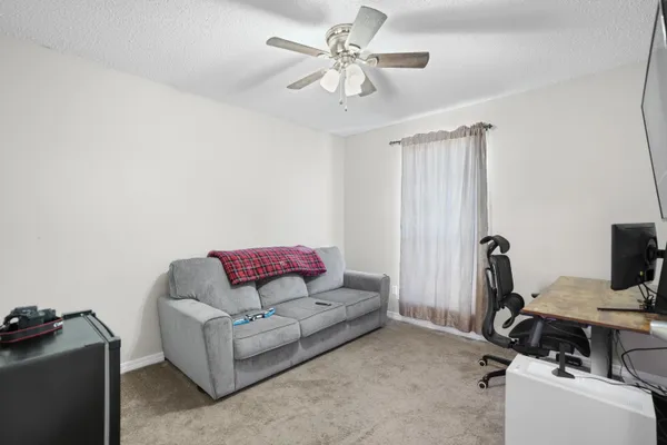 a living room with furniture a ceiling fan and a window