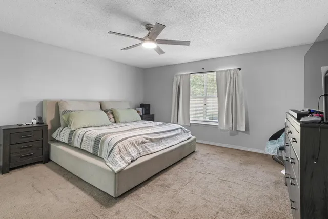 a spacious bedroom with a bed and a flat tv screen on the dresser