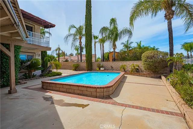 a swimming pool with outdoor seating yard and palm trees