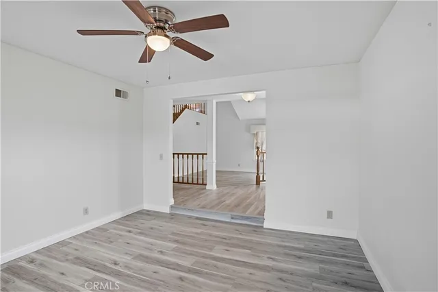 an empty room with wooden floor and a ceiling fan
