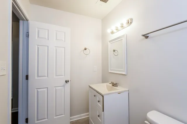 a bathroom with a toilet sink vanity and mirror