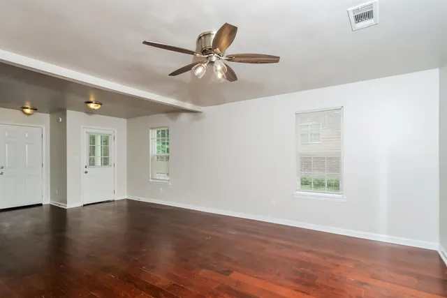 a view of an empty room with wooden floor and a window