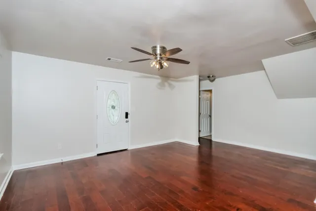 an empty room with wooden floor and a ceiling fan