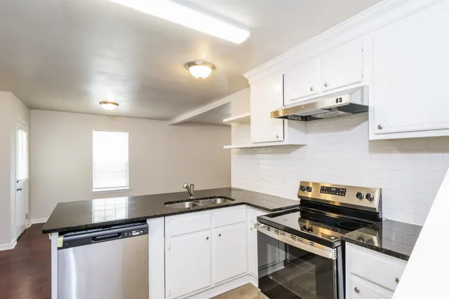 a kitchen with stainless steel appliances a sink dishwasher a stove and white cabinets