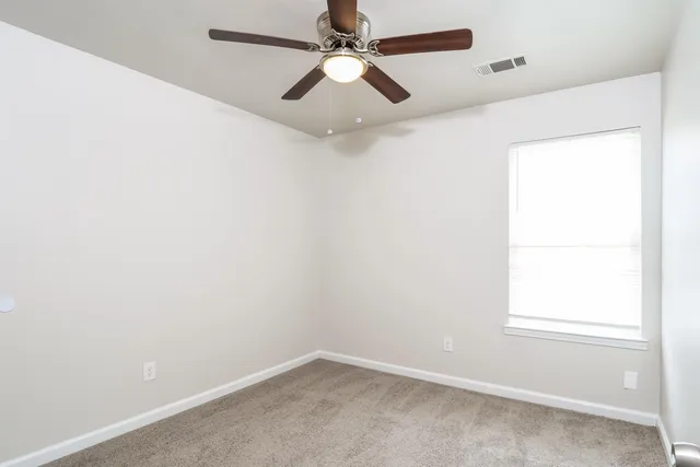 an empty room with a window and a fan