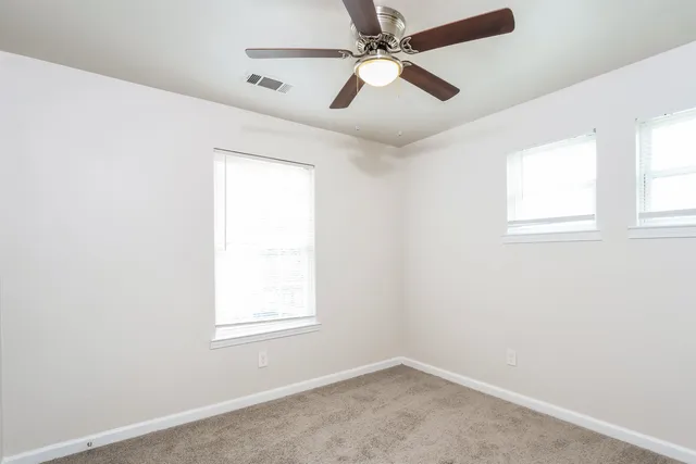 an empty room with a window and a fan
