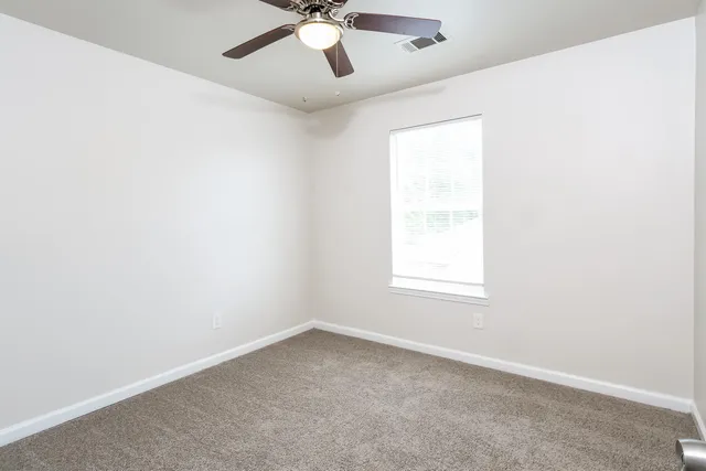 an empty room with a window and a fan