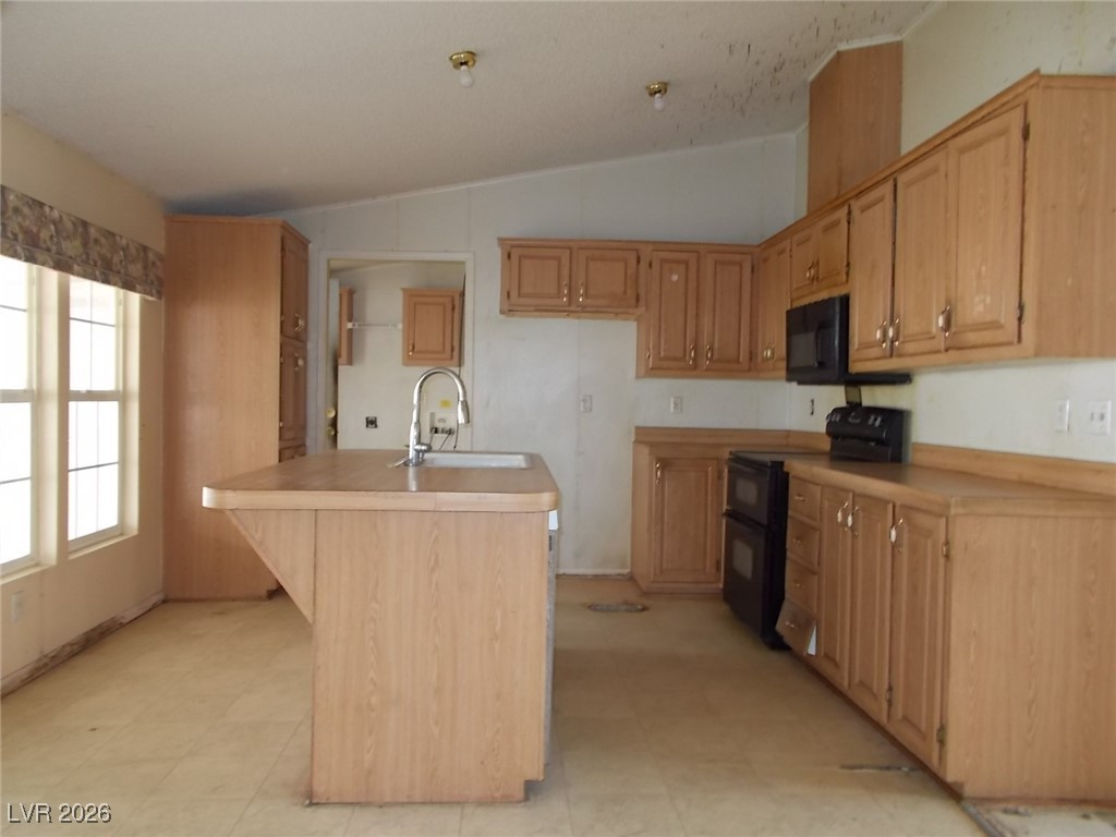 171 Paradise Road Alamo, NV 89001 - Photo 6 of 21 Kitchen with lofted ceiling, black appliances, light countertops, a kitchen bar, and a center island with sink