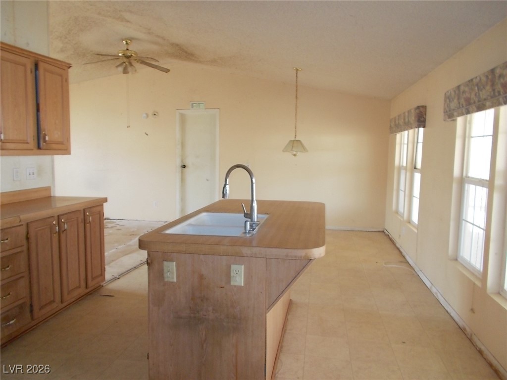 171 Paradise Road Alamo, NV 89001 - Photo 7 of 21 Kitchen featuring vaulted ceiling, light countertops, decorative light fixtures, a kitchen island with sink, and a ceiling fan