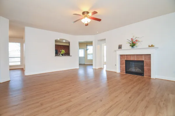 a view of an empty room with wooden floor fireplace and a window