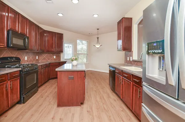 a large kitchen with stainless steel appliances wooden floors and wooden cabinets