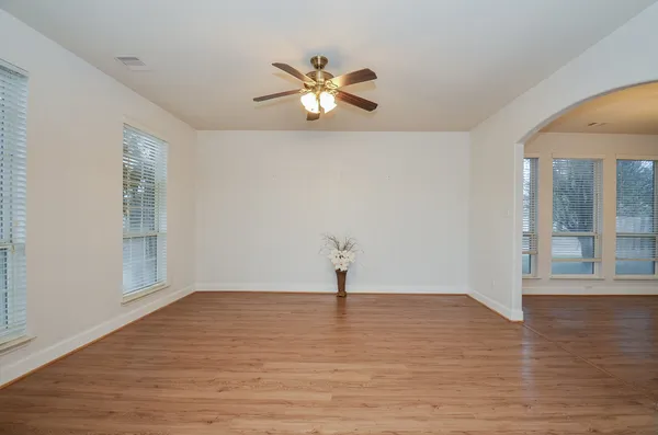a view of empty room with wooden floor and fan