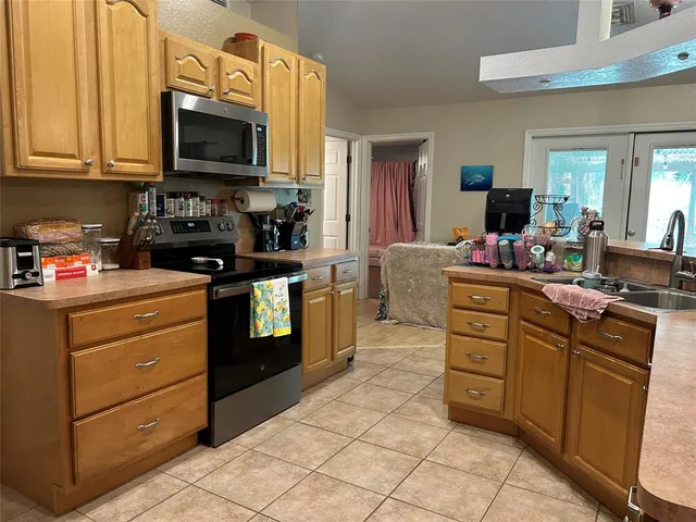 a kitchen with stainless steel appliances granite countertop a stove top oven a sink dishwasher and white cabinets with wooden floor