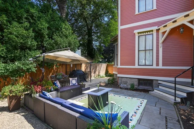a view of a patio with couches table and chairs under an umbrella with a barbeque