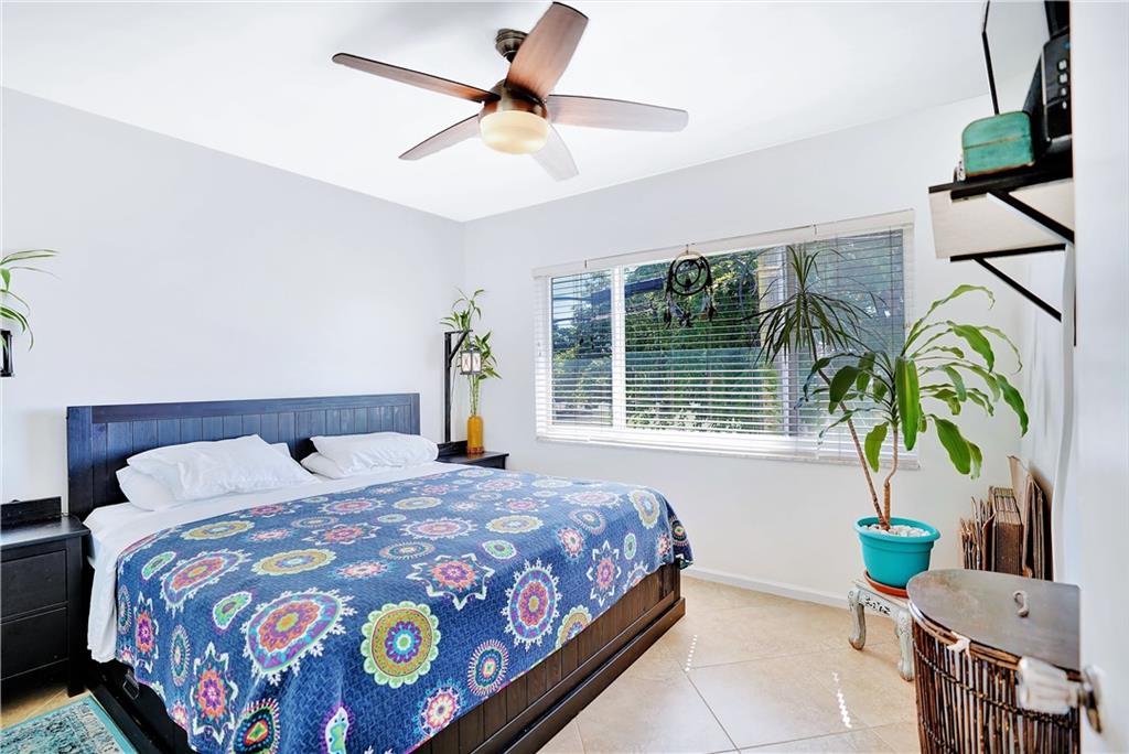 5700 Northeast 22nd Way, Unit 322 Fort Lauderdale, FL 33308 - Photo 11 of 19 a bedroom with a bed a chandelier and a window