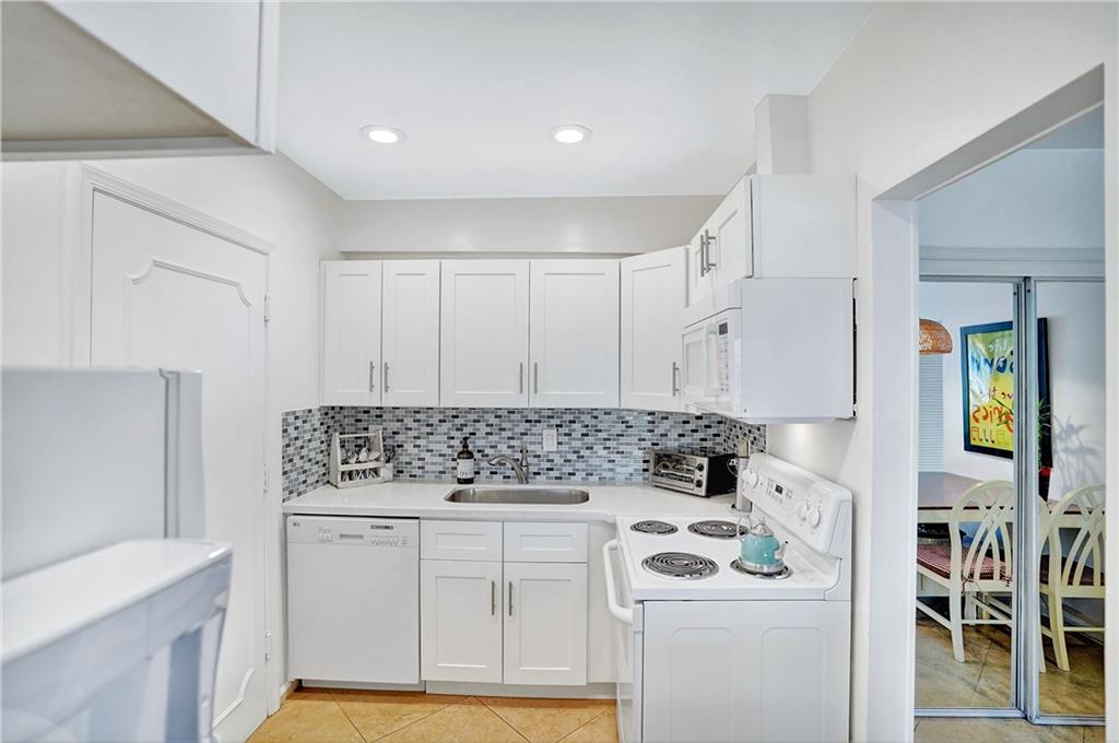 5700 Northeast 22nd Way, Unit 322 Fort Lauderdale, FL 33308 - Photo 5 of 19 a kitchen with white cabinets and white appliances