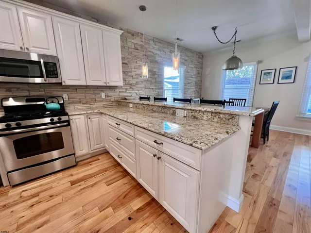 a kitchen with stainless steel appliances granite countertop a stove a sink and white cabinets