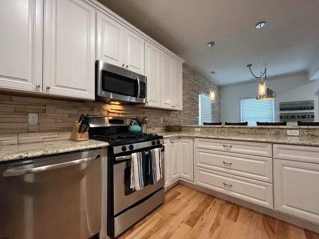 a kitchen with stainless steel appliances granite countertop a sink a stove and a microwave