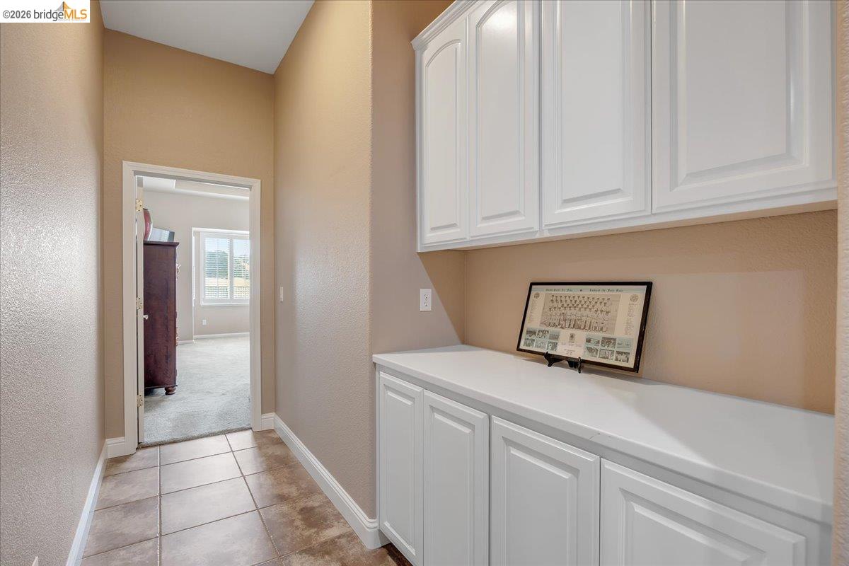 158 Rock Ridge Lane Copperopolis, CA 95228 - Photo 29 of 72 Hallway featuring tile flooring, white baseboards, and built-in white cabinetry with a light-colored countertop