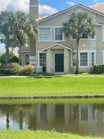 a front view of a house with a yard and a pond