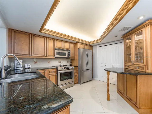a kitchen with stainless steel appliances granite countertop a stove a sink and a refrigerator