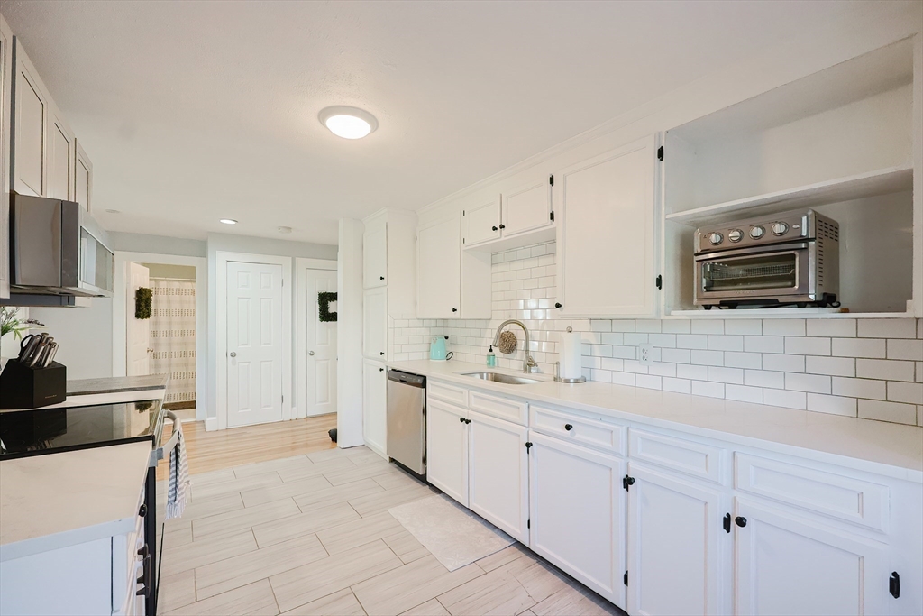 321 Shears Street Wrentham, MA 02093 - Photo 7 of 39 a large white kitchen with stainless steel appliances granite countertop a sink and a stove
