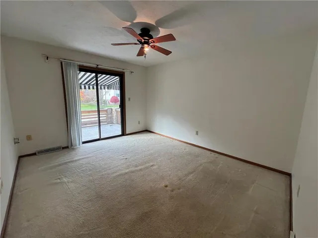 an empty room with a ceiling fan and window