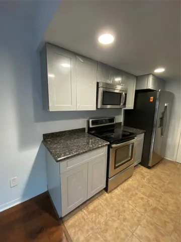 a kitchen with stainless steel appliances granite countertop a stove a sink and a microwave