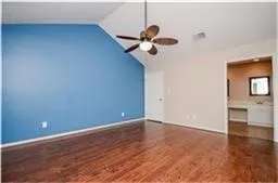 an empty room with a ceiling fan and wooden floor