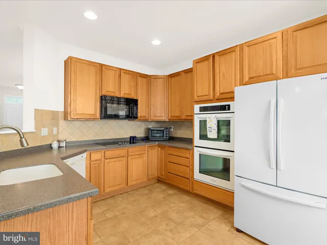 a kitchen with stainless steel appliances granite countertop a refrigerator a stove top oven a sink and dishwasher