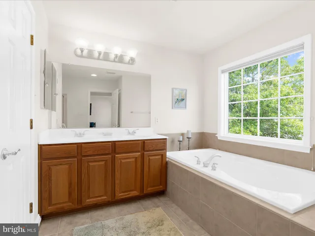 a bathroom with a tub a sink and mirror