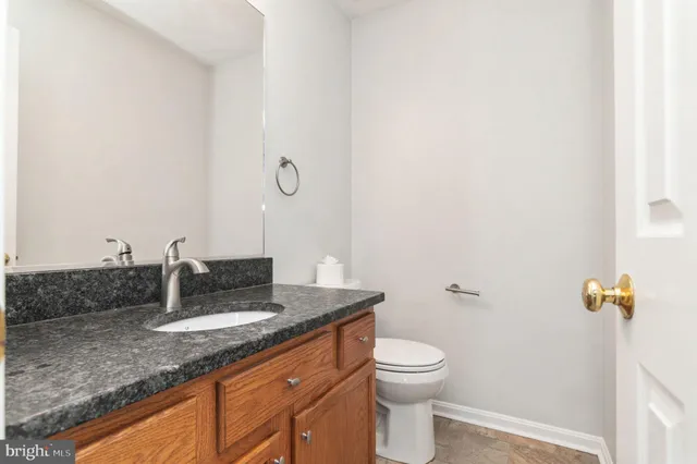a bathroom with a granite countertop sink a toilet and a mirror