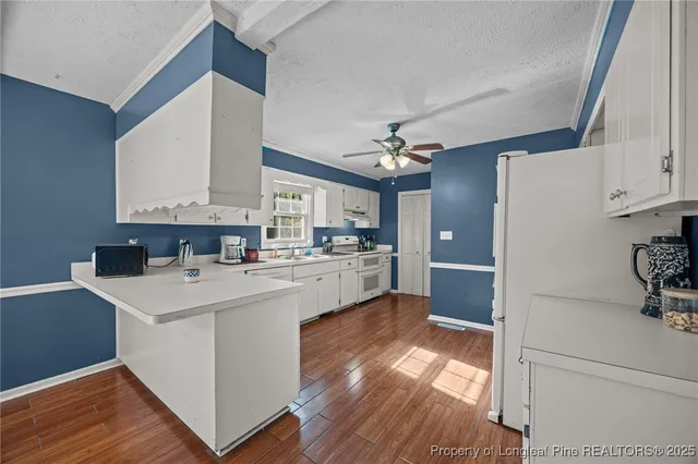 a kitchen with a refrigerator a white cabinets and wooden floor