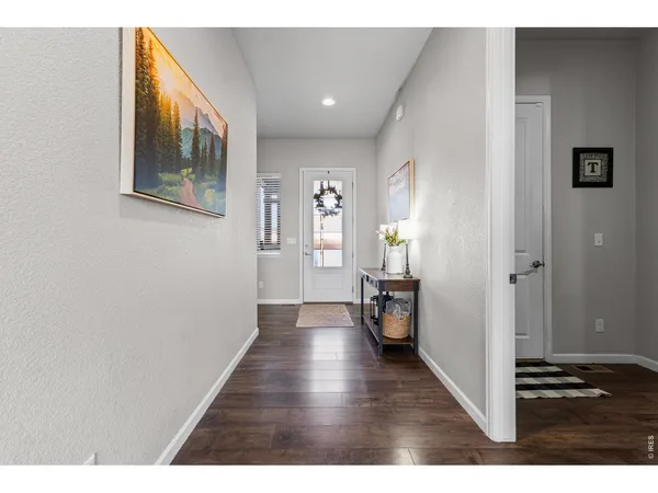 a view of a hallway with wooden floor and furniture