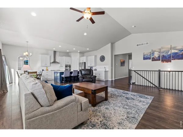 a living room with furniture kitchen view and a wooden floor