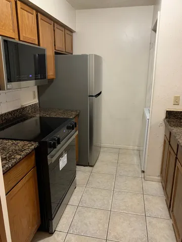 a kitchen with granite countertop a refrigerator and a stove top oven