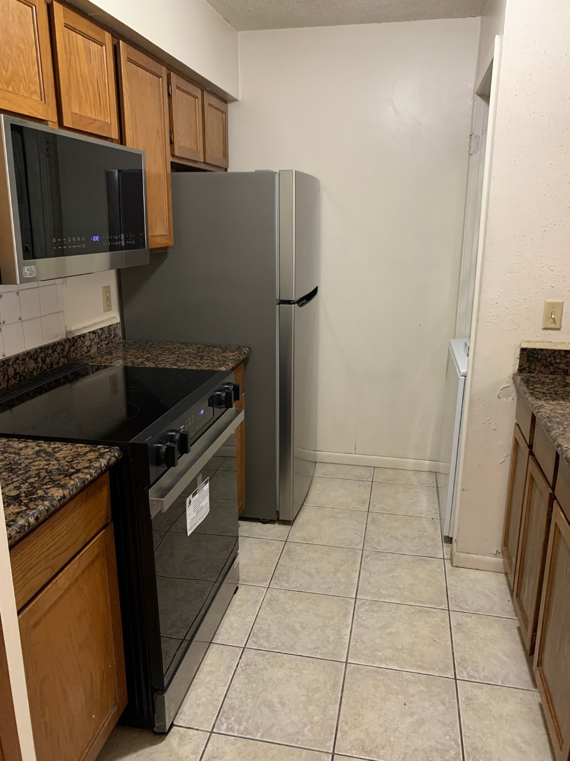2277 South Kirkwood Road, Unit 708 Houston, TX 77077 - Photo 5 of 13 a kitchen with granite countertop a refrigerator and a stove top oven