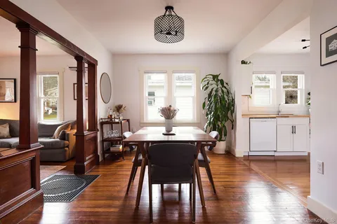 a dining room with wooden floor a chandelier a wooden table and chairs