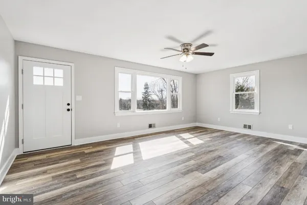 a view of empty room with wooden floor and fan