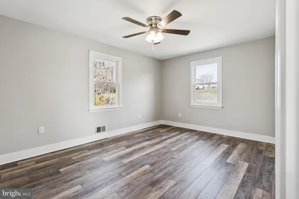 a view of an empty room with window and wooden floor