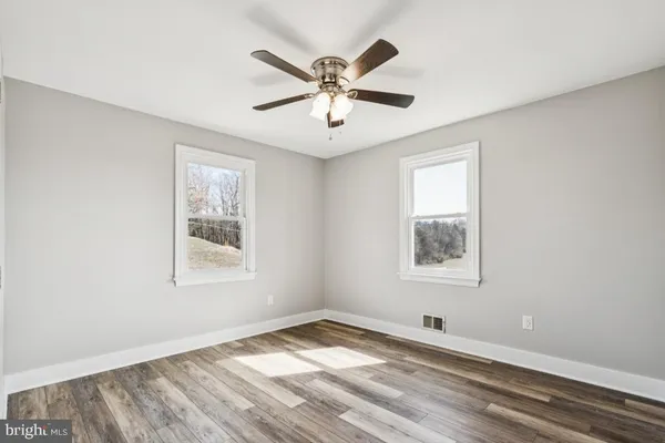 a view of empty room with wooden floor and fan