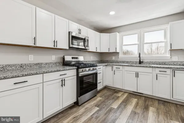 a kitchen with granite countertop white cabinets white stainless steel appliances and sink