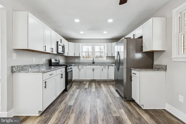 a kitchen with a white cabinets and wooden floor